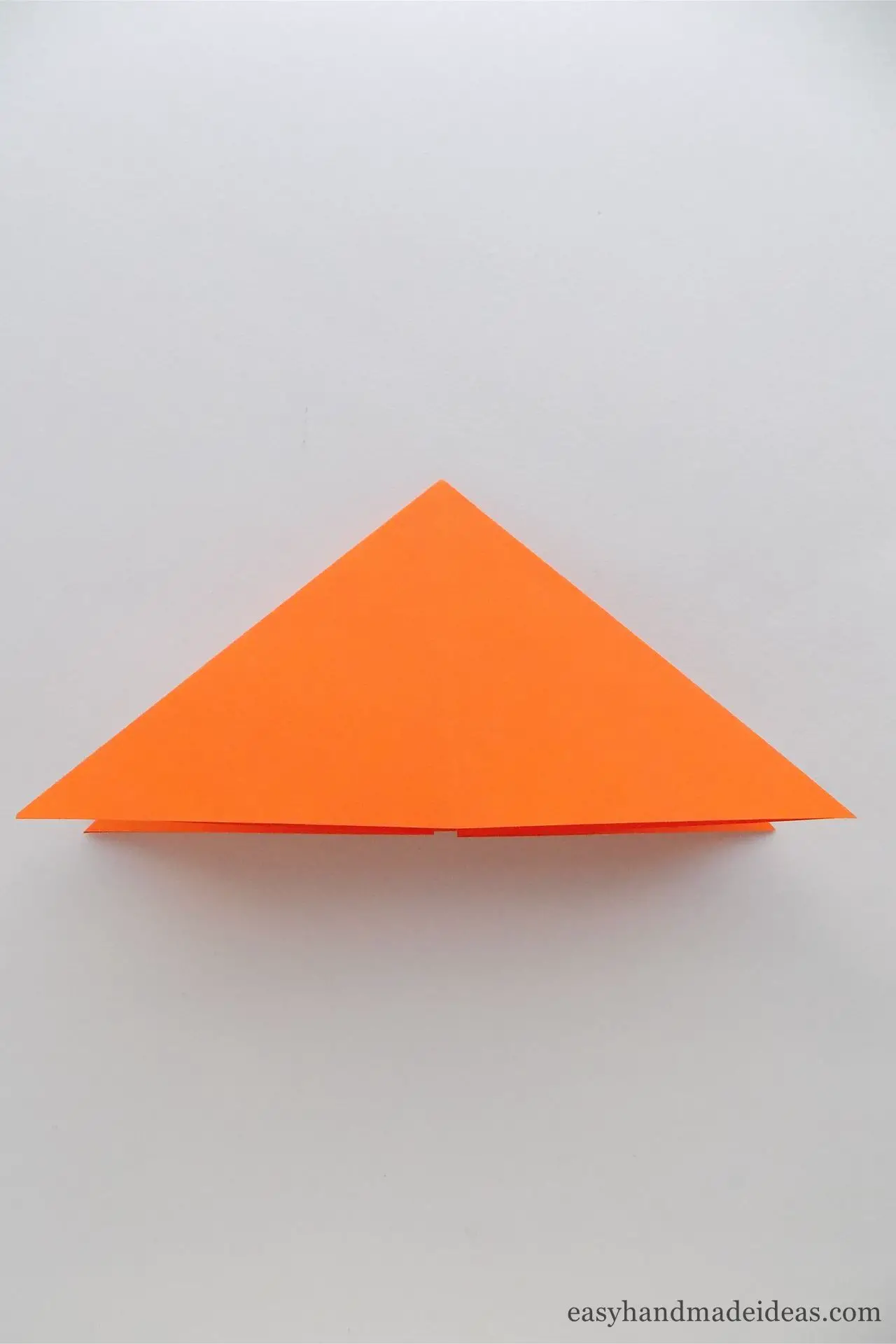 Fold both sides of the square inward to make a triangle